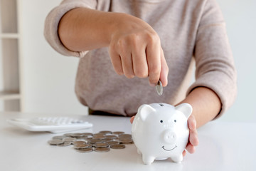 Obraz na płótnie Canvas Women are putting coins in the piggy bank Saving money with coins Step into a business that is growing to be successful and save for retirement ideas