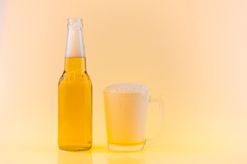 Bottle and Glass of cool beer with foam, clipping path, bubbles in a drink, on abstract orange background.