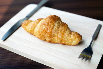 Freashly baked tasty croissants on wooden background.