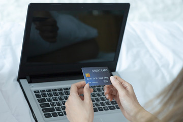 Fototapeta na wymiar Asian woman paying online. Shopper shopping online with credit card and laptop on bed in home.shopping online concept.