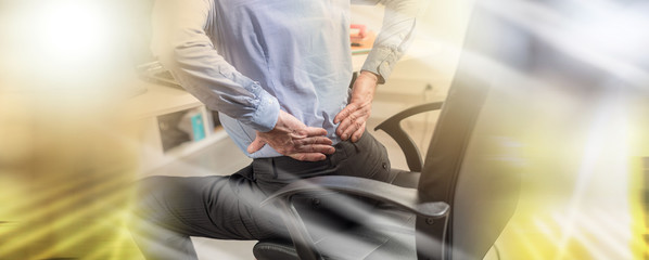 Businessman suffering from back pain, light effect; multiple exposure