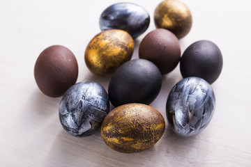 Holidays, minimalism, traditions and Easter concept - Dark stylish easter eggs on white wooden background.