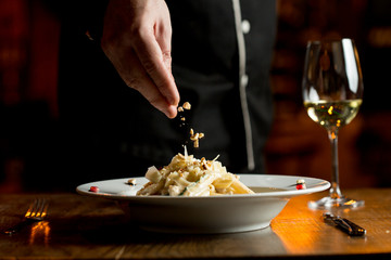 Adding hazelnuts to penne with chicken and spinach in parmesan sauce