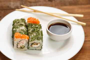 Set of rolls with dill and salmon on a white plate with soy sauce.