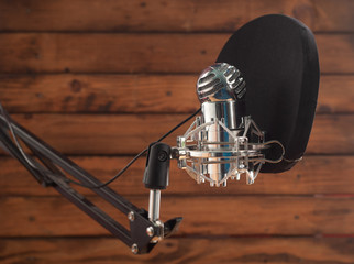 Condenser microphone and pop filter on a wooden background, room for recording podcasts,