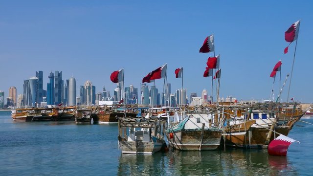 Traditional Dhow, Arab sailing vessels with Qatar flags in the harbour with the Doha skyline in the background