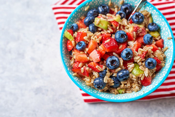 healthy oatmeal with fruits and berries, strawberries, blueberries and figs in a blue bowl on a gray background, for Breakfast. Top view