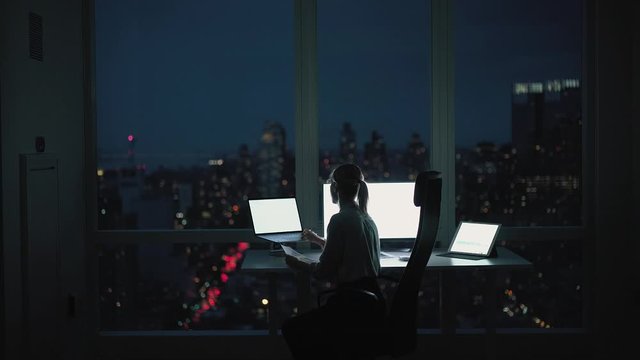 Back view of corporate director sitting in orthopedic chair near office desktop and working with financial report while using modern digital technology for checking web information
