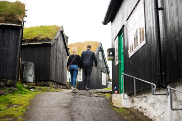 Couple holding hands walking through rustical village at North Europe