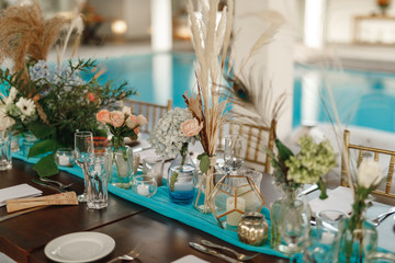 Wedding Table Setting With Floral Arrangement. Decorated beautiful table with candles at the celebration. Wedding. Birthday. Romantic dinner in garden. Anniversary. Beautiful glassware. Sunlight.