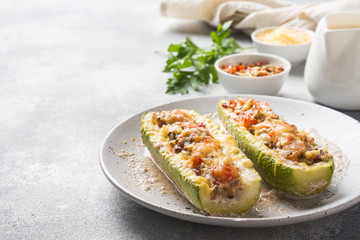 Baked stuffed zucchini boats with minced chicken mushrooms and vegetables with cheese on a plate. Copy space