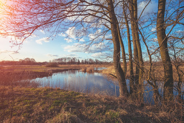Obraz premium View of a winding river on the meadow in evening at sunset light. Beautiful nature landscape with the bright evening sky