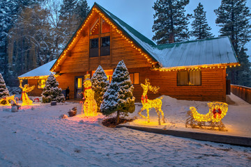 Holidays with Christmas decorations and lights, cedar chalet home with snow and front porch.