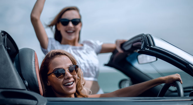 close up.two happy young women in a convertible car - Powered by Adobe