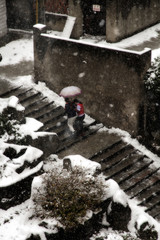 On the snowy stairs, a couple is supporting each other and slowly walking home with umbrellas.