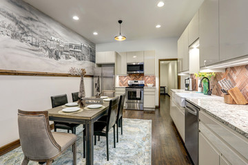 Dining room with rustic mural of old village and modern kitchen shiny beige cabinets, rustic brick backsplash.