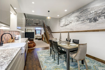 Dining room with rustic mural of old village and modern kitchen shiny beige cabinets, rustic brick backsplash.