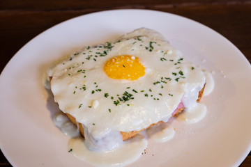 Sandwich with ham and cheese and eggs on white plate