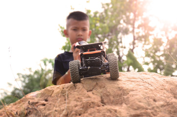 the boy in black shirt control the car toy on the soil hill, concept for stay and play at home to fighting covid-19. Fun time with toy in vacation and hiliday time.