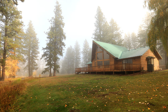 Cedar A frame chalet house in the forest during fall with foggy landscape exterior