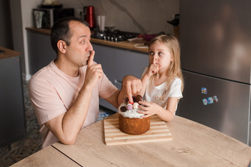 Father and daughter trying to taste easter cake. Easter concept.