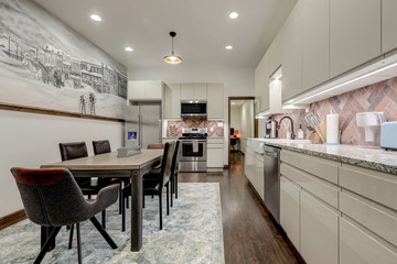 Dining room with rustic mural of old village and modern kitchen shiny beige cabinets, rustic brick backsplash.