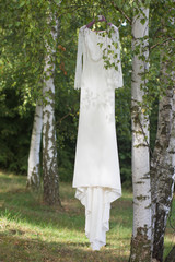 beautiful wedding dress hanging on the tree