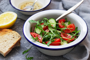 Salad with arugula, tomatoes, cucumbers and lemon sauce.