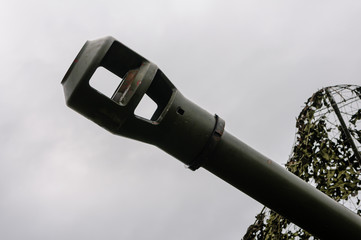 Muzzle of a 105mm Light Artillery Gun pokes through camouflage netting in a field