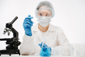 Fototapeta premium female scientist in protective uniform making coronavirus test with reagents at table with microscope in modern lab