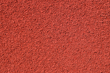 Textured detail photo of red pellets used to construct a running track