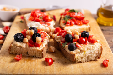 Mix of bruschette with cherry tomatoes and cream cheese, hummus and black olives. Italian food, healthy appetizer