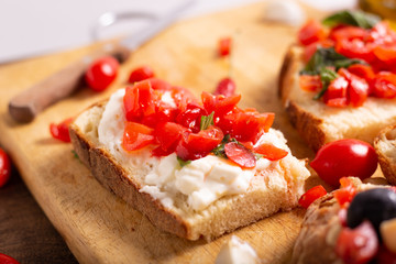 Fototapeta na wymiar Mix of bruschette with cherry tomatoes and cream cheese, hummus and black olives. Italian food, healthy appetizer