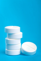 Several white pills on a blue background. Macro photo. Close-up. Free space for text.
