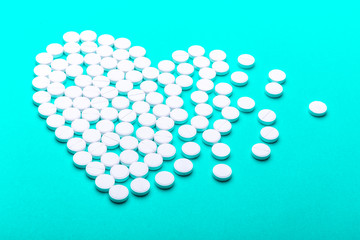 Heart of pills on a green background.