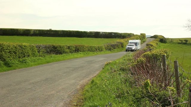 Car & Caravan (Trailer) driving down the road / country lane on a summer day - Staycation. Stock Video Clip Footage