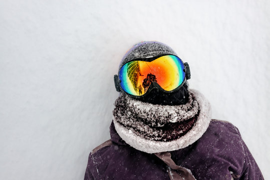 Kind mit M&uuml;tze und Skibrille liegt im Schnee MR: yes