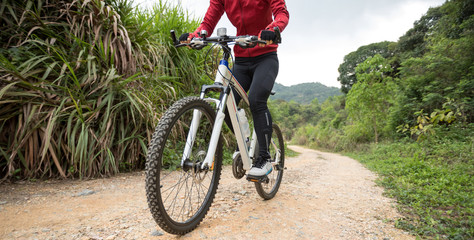 Woman cyclist riding a bike on a nature trail in the mountains