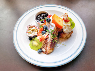 Delicious sweets French toasts with vanilla yogurt, blueberries jam and fresh fruits for a vitamin breakfast.