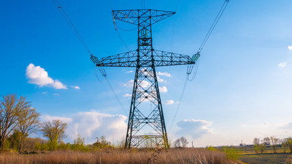 High voltage power line in a field with clouds in the background