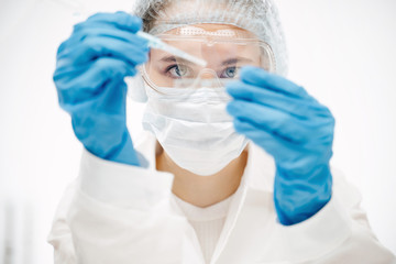 young woman in protective gloves making coronavirus test with special reagent in laboratory extreme...