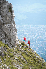 Climbers man and woman stanign on the edge of the rock