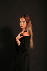 Fototapeta premium Studio portrait of pretty woman in black dress on dark background