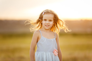 Fototapeta na wymiar kid girl grey dress stand on sloping wheat field
