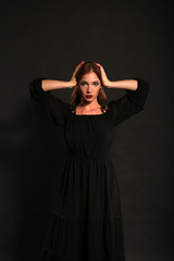 Studio portrait of pretty woman in black dress on dark background