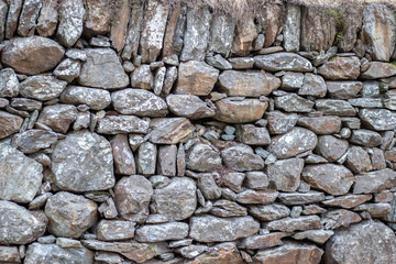 Many gray old stones piled into a stone wall. Barrier of stones