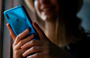 Woman using blue mobile phone at home.