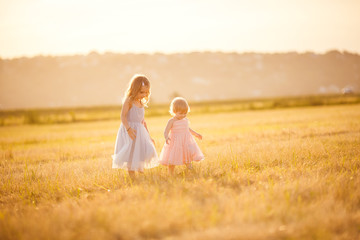 Fototapeta na wymiar little girls going on sloping wheat field sunset