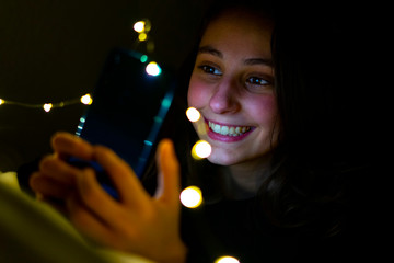 Woman using the phone at night in bed.