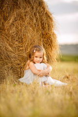 little girl sit near stack of hay village summer